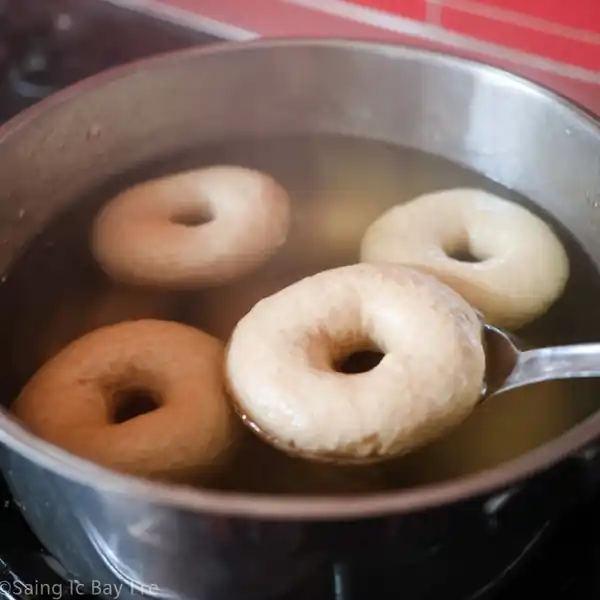 Everything Bagel You’ll Love, Easy, Homemade & High Protein 17 raw everything bagel boiling in water inside a red pot on stovetop