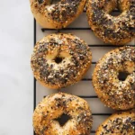 Everything Bagel You’ll Love, Easy, Homemade & High Protein 12 golden brown everything bagel topped with poppy seeds, sesame, and spices on cooling rack
