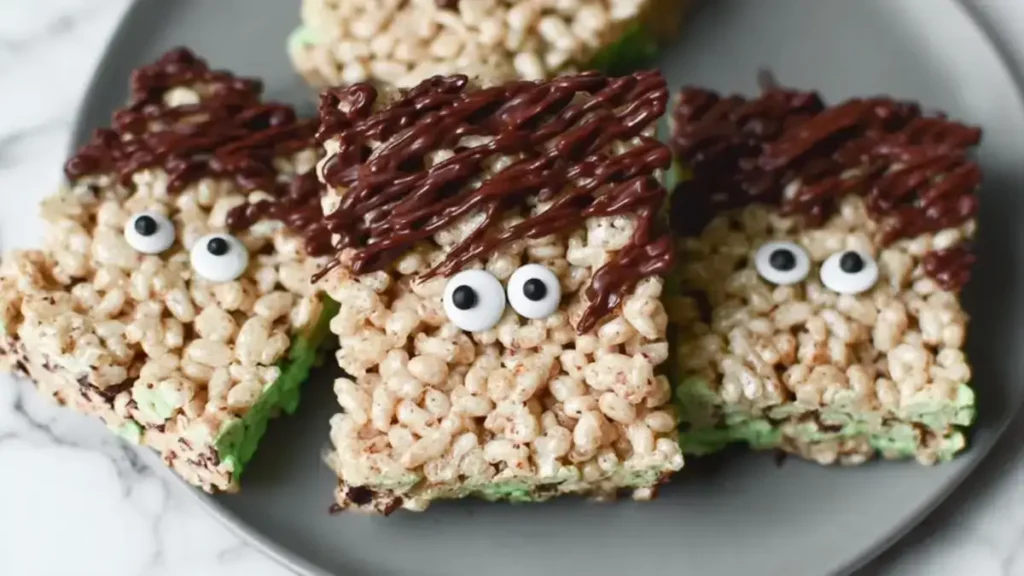 Frankenstein Rice Krispies Treats 4 Frankenstein-inspired rice krispie treats with chocolate hair and candy eyes on marble plate