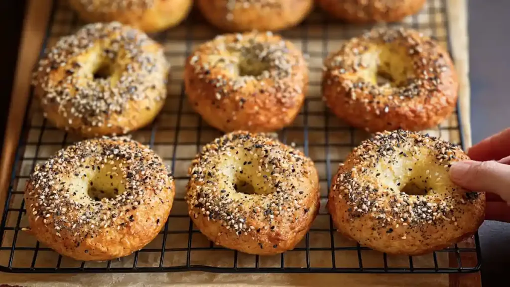 freshly baked protein bagels cooling on a wire rack with sesame and poppy seeds