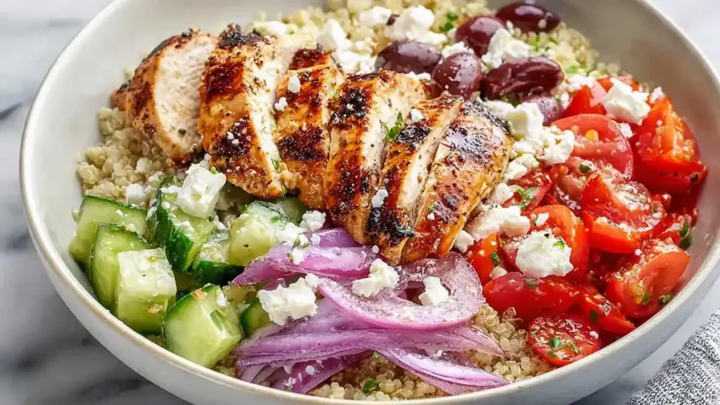 grilled chicken quinoa bowl with cherry tomatoes, cucumbers, kalamata olives, red onion, and feta