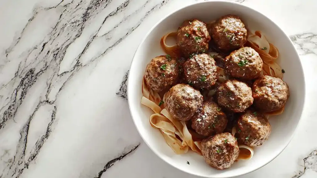 Turkey Meatballs 3 Juicy Italian meatballs served over wide pasta noodles in white bowl with sauce