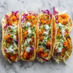 spicy grilled shrimp tacos with cabbage slaw, cilantro, lime wedges, and creamy sauce
