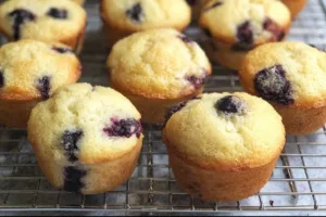 Freshly baked blueberry mini muffins stacked on a plate.
