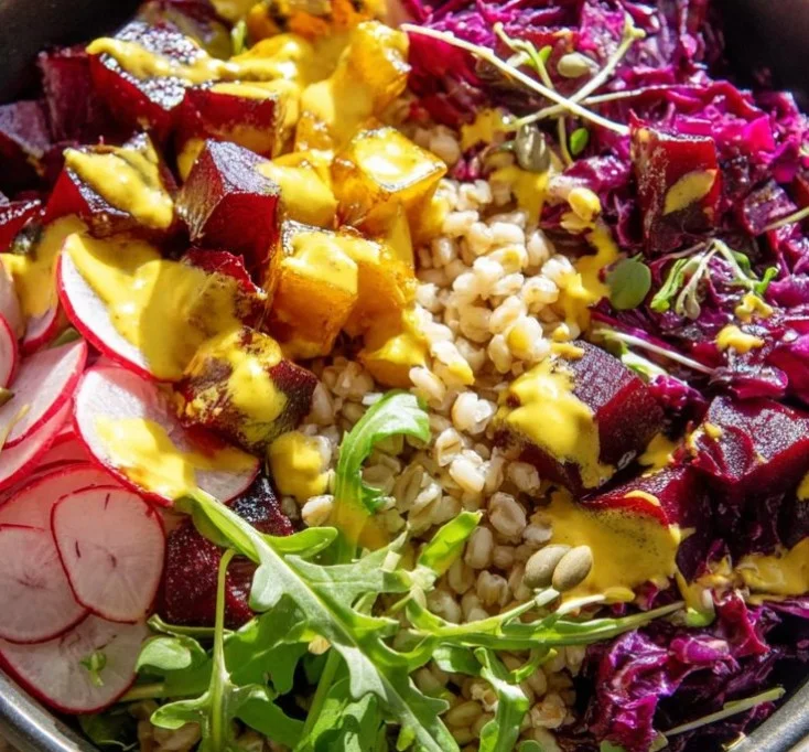 A vibrant roasted beets bowl filled with fresh greens, nuts, and dressing.