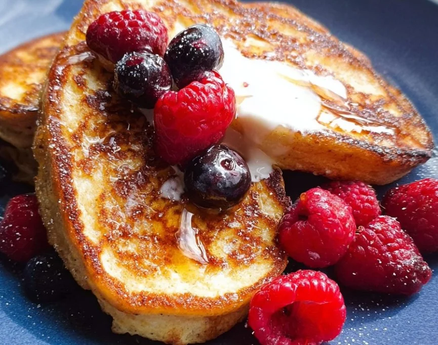 Fluffy American pancakes stacked on a plate with syrup and berries