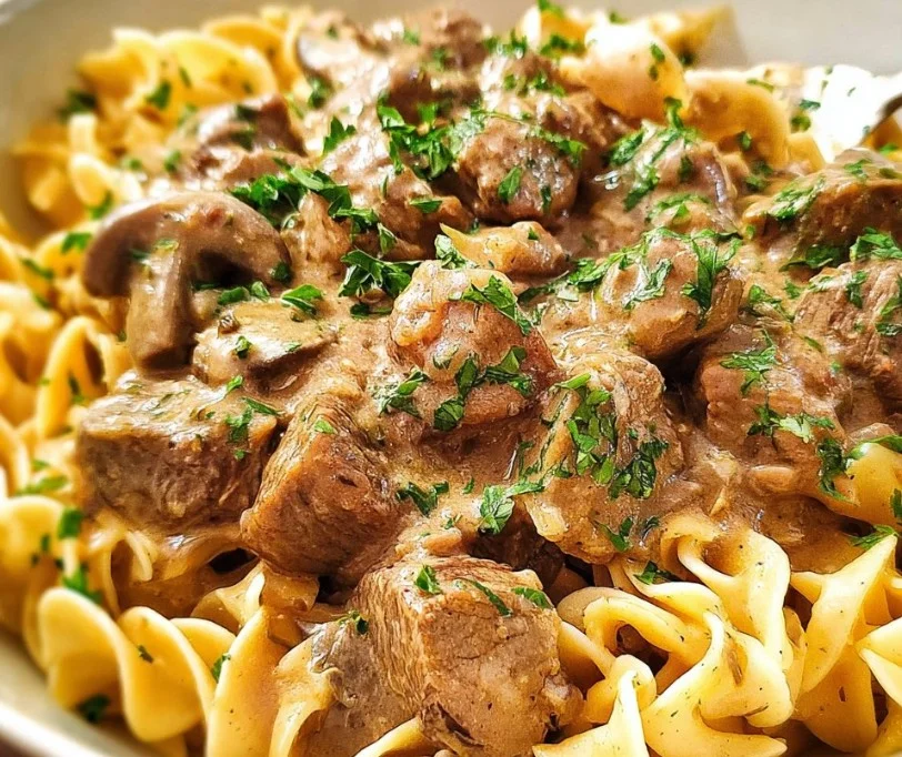 Slow cooker beef stroganoff served with egg noodles and fresh herbs.