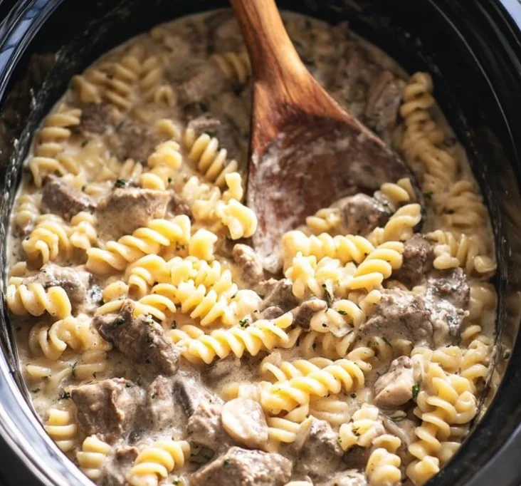 Slow Cooker Beef Stroganoff served in a bowl with noodles and garnished with parsley
