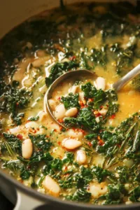 Bowl of creamy white bean soup with kale and herbs garnished on top