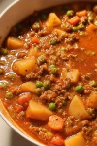 A bowl of hearty ground beef stew with vegetables and herbs