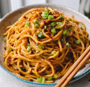 Dish of vegan garlic noodles topped with fresh herbs and garlic