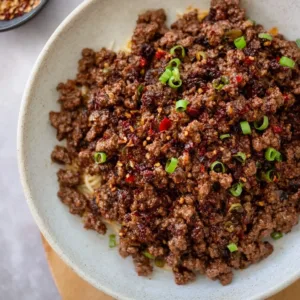 Crispy Firecracker Ground Beef served in a bowl with garnishes and spices.