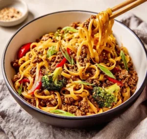 Spicy Firecracker Beef Noodles topped with fresh herbs and chili peppers.