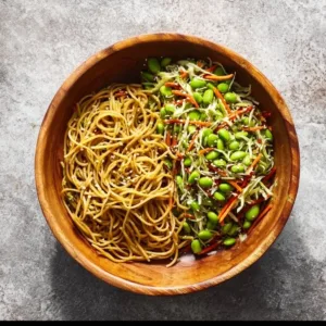 Cold sesame edamame noodles dish garnished with sesame seeds and green onions.