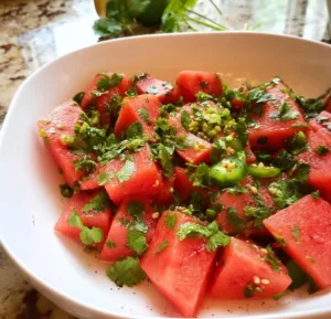 Spicy watermelon salad garnished with herbs and spices for a refreshing summer dish
